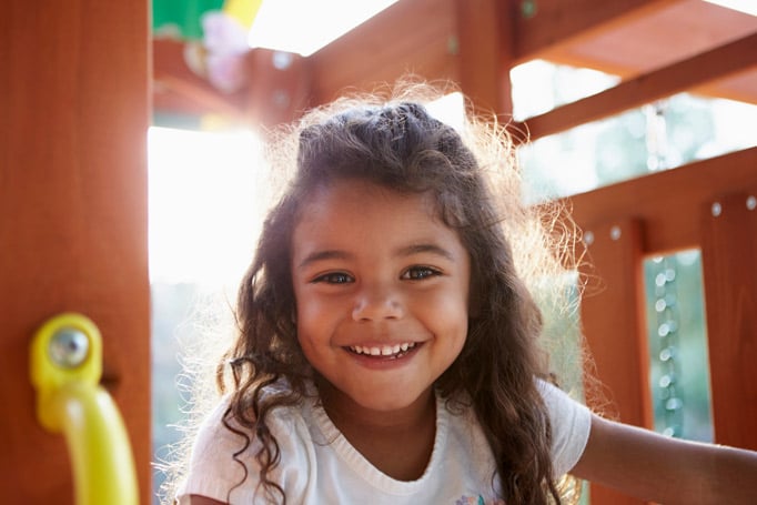 Little girl playing in a playhouse outside